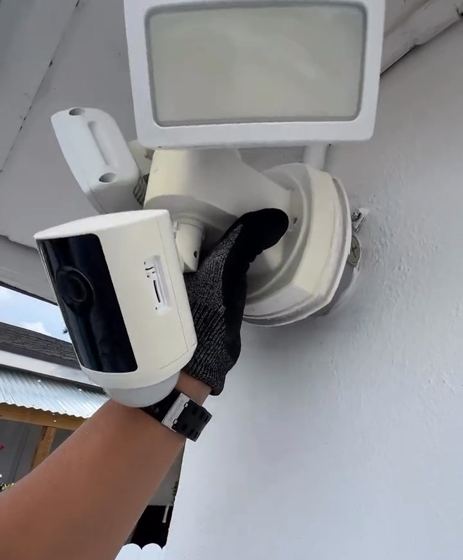 Instalación de cámara de seguridad con reflector en la fachada de una casa